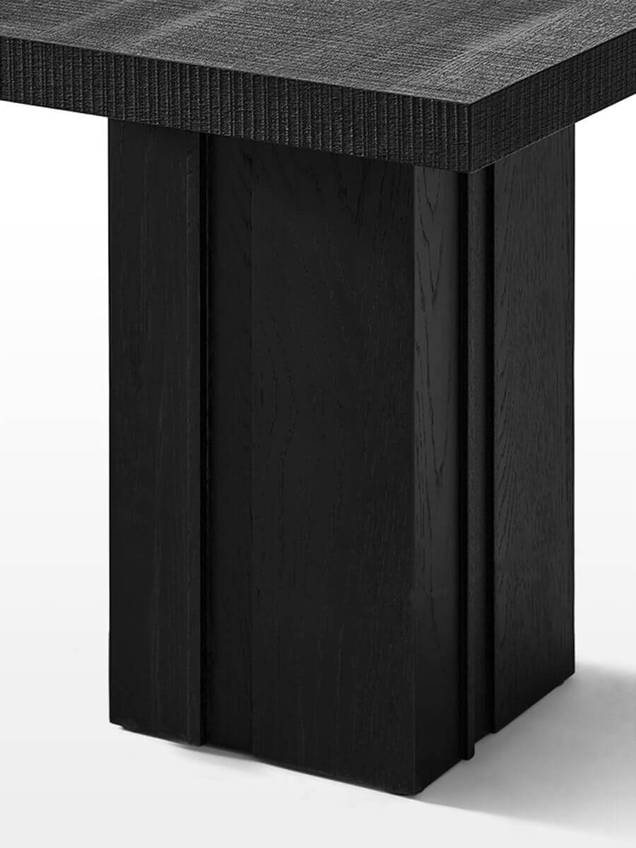 Close-up of the Anya oak side table showing the sculptural architectural base and textured black oak finish.