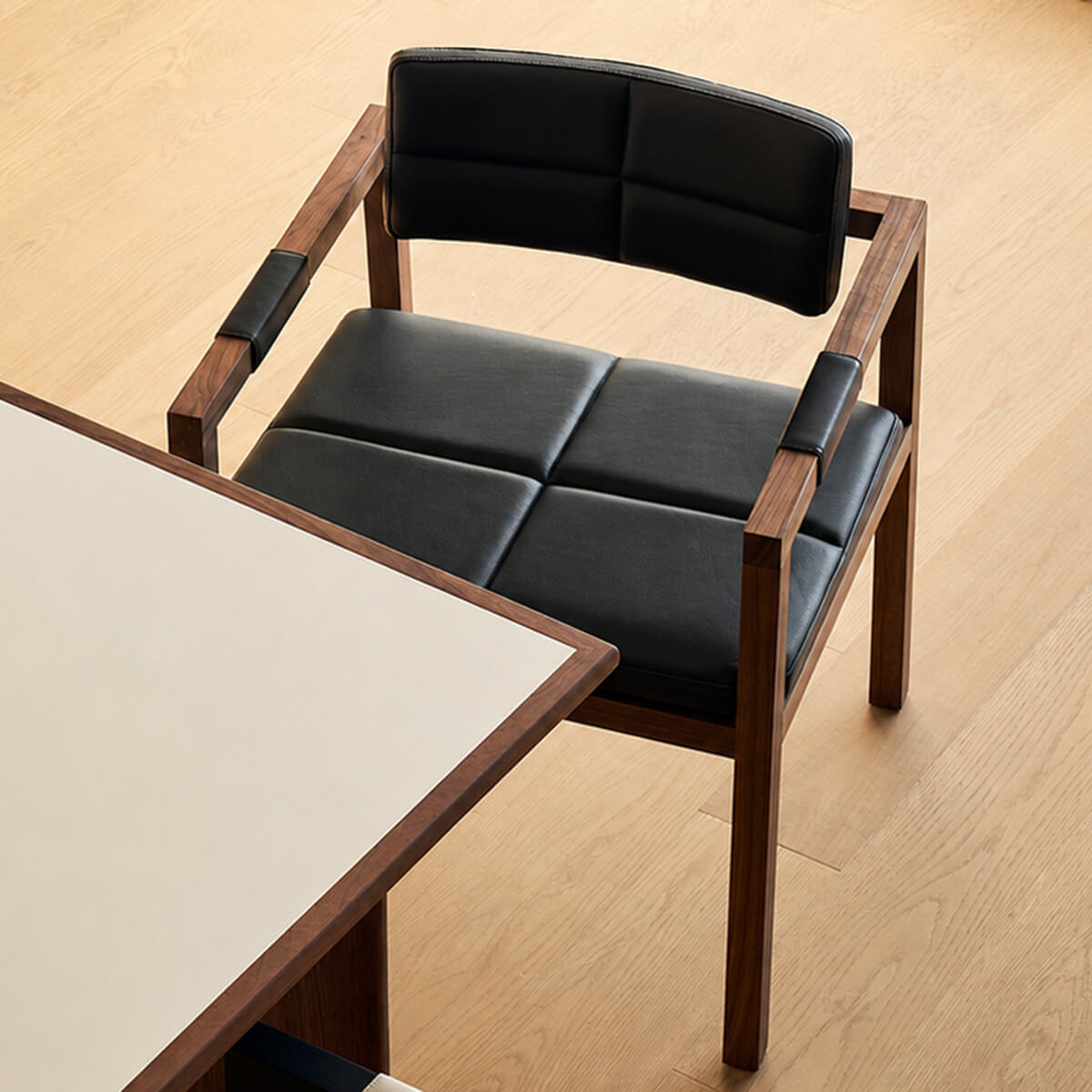 Arden dining chair with full grain leather and solid walnut frame beside a modern dining table