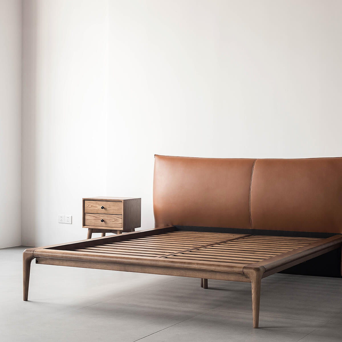 Angled view of the Arnold Solid Ash Bed Frame with leather headboard