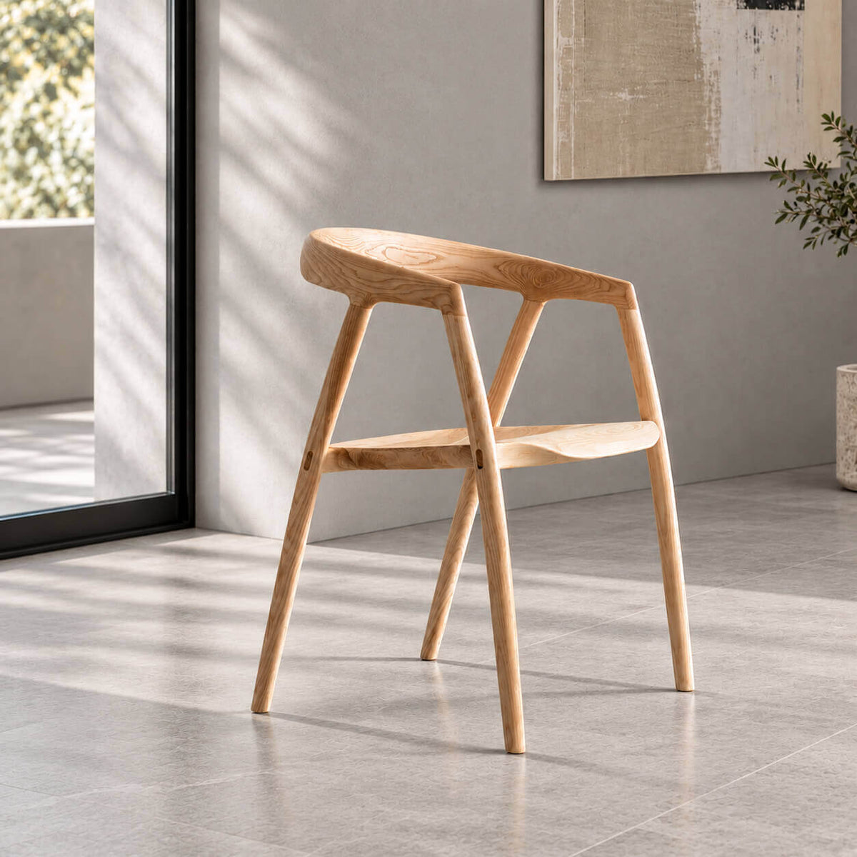 Bata solid ash wood dining chair in natural finish, featuring a sculpted curved backrest and contoured wooden seat in a minimalist grey interior.