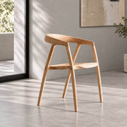 Bata solid ash wood dining chair in natural finish, featuring a sculpted curved backrest and contoured wooden seat in a minimalist grey interior.