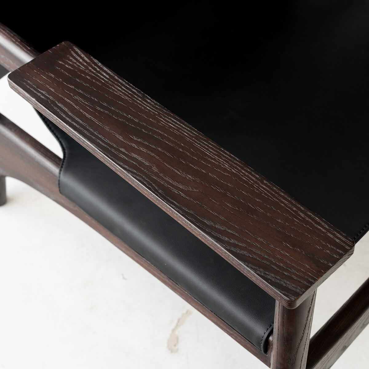 Close up detail of the Carey armchair dark ash timber armrest