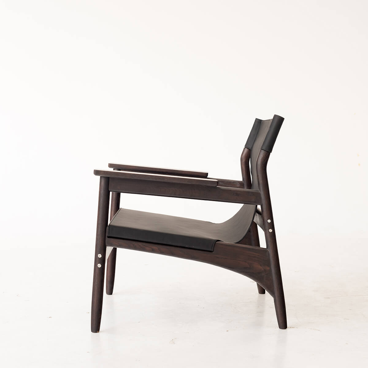 Carey armchair with dark ash timber frame and black sling seat side view