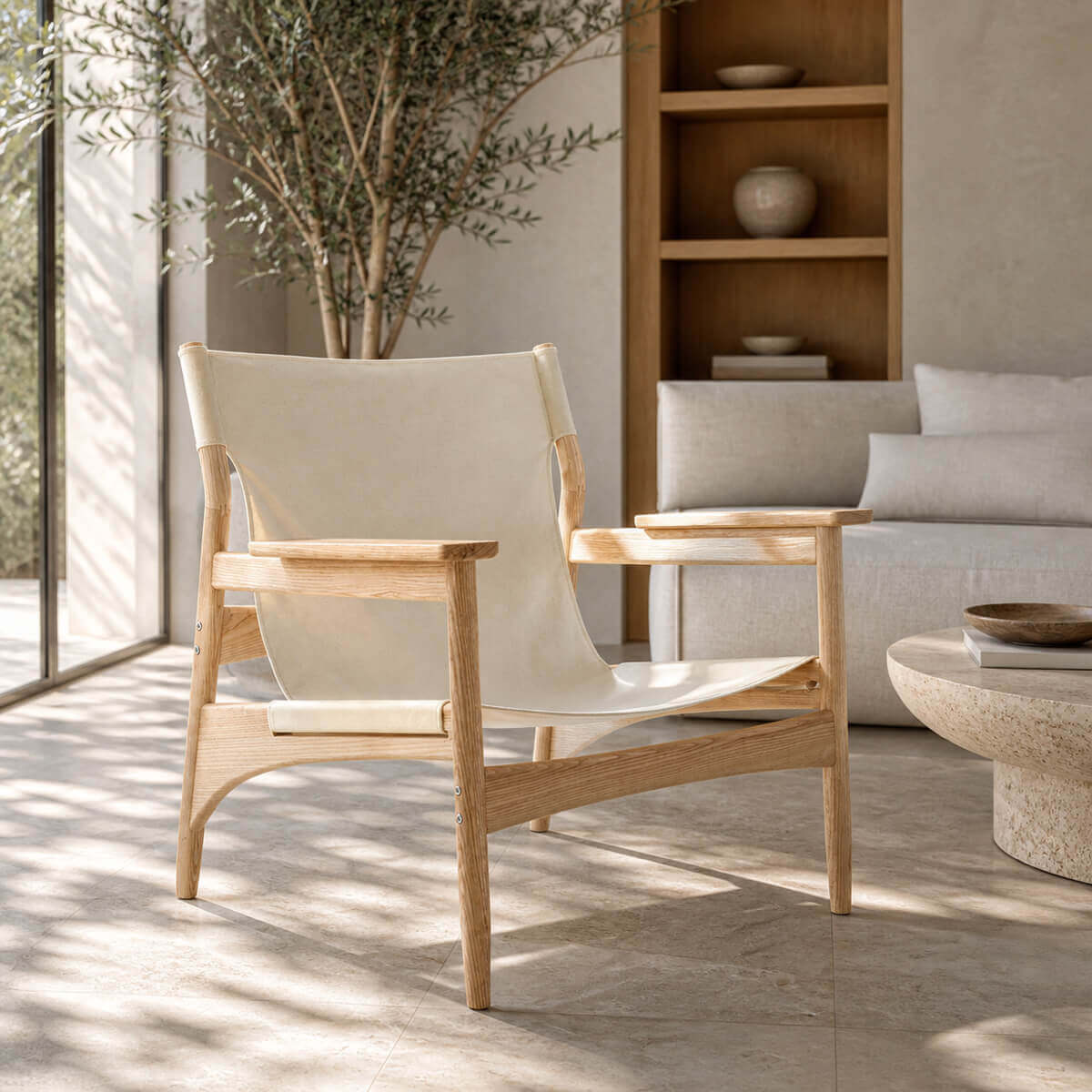 Carey armchair with natural ash timber frame and canvas sling seat in a bright living room