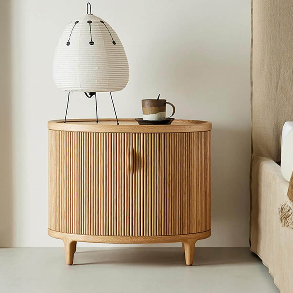Charlie Tambour Bedside Table in Oak beside a bed