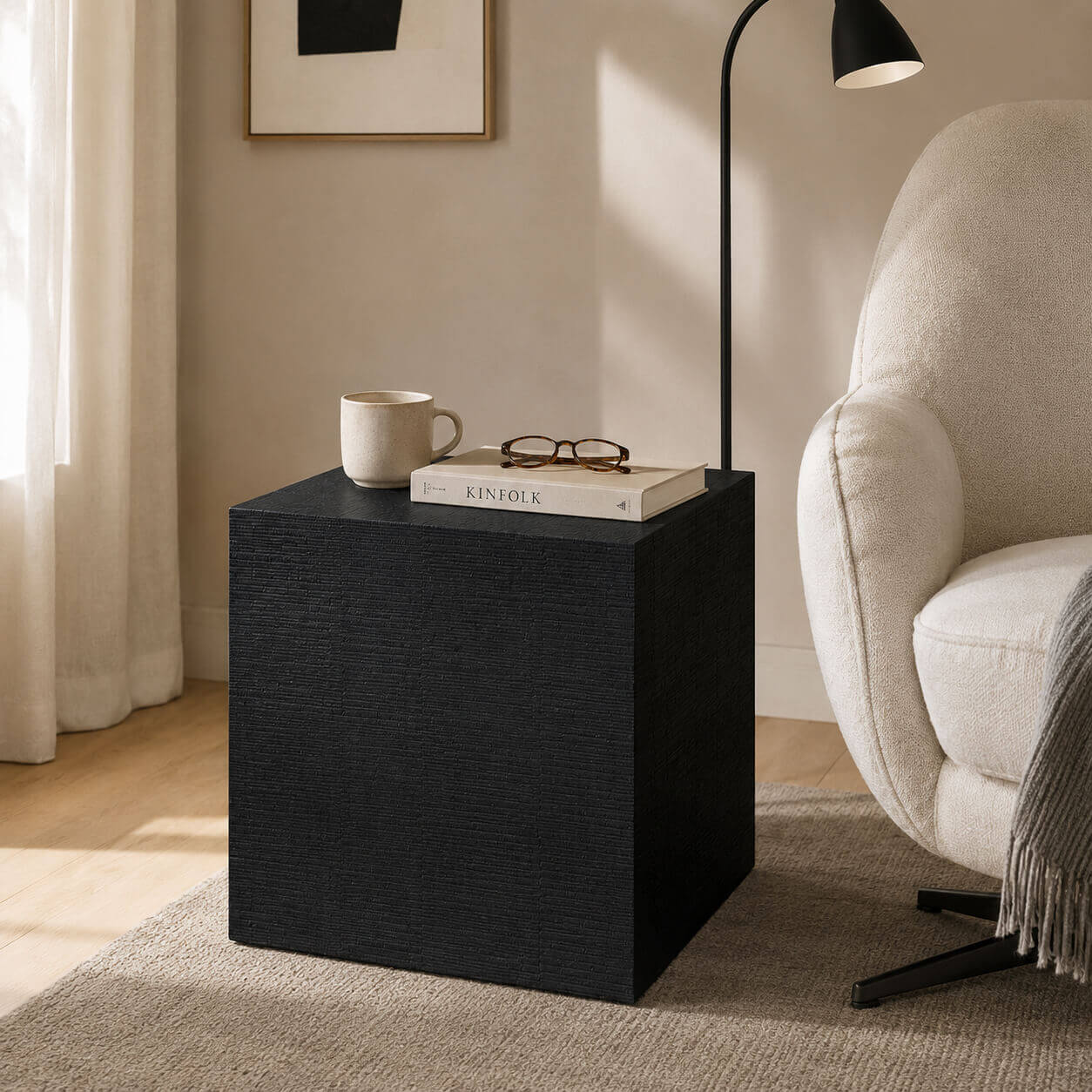 Clara Cube Side Table in black finish styled beside a lounge chair in a modern reading corner.