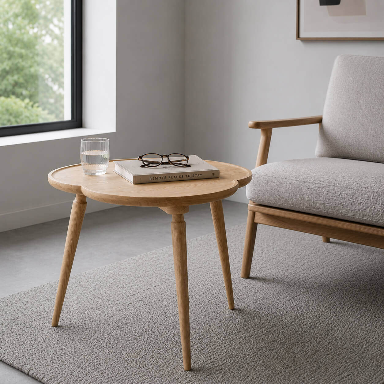 Cloudy solid ash side table beside a modern sofa with a book, glasses and water glass in a neutral living room.