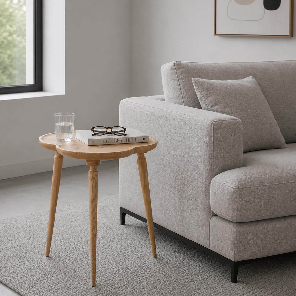 Cloudy solid ash side table styled beside a contemporary sofa in a bright neutral living room.
