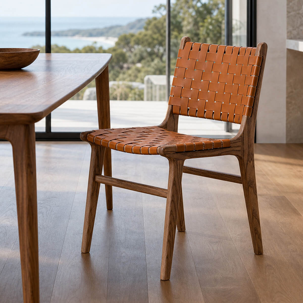 Connar dining chair with woven saddle leather seat and backrest beside a walnut dining table