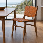 Connar dining chair with woven saddle leather seat and backrest beside a walnut dining table