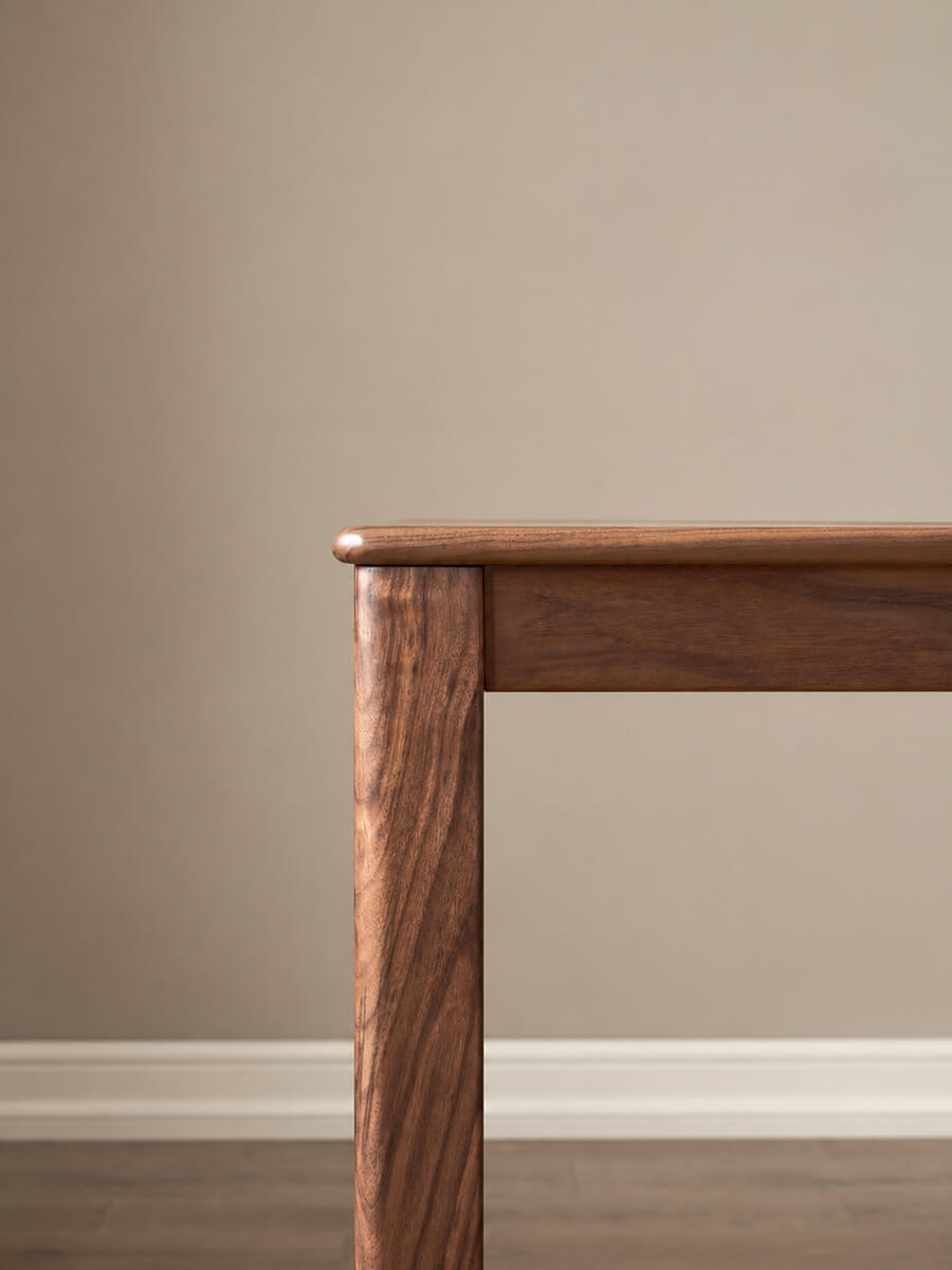 Close-up of Dalton solid walnut dining table showing rounded tabletop corner and solid timber leg