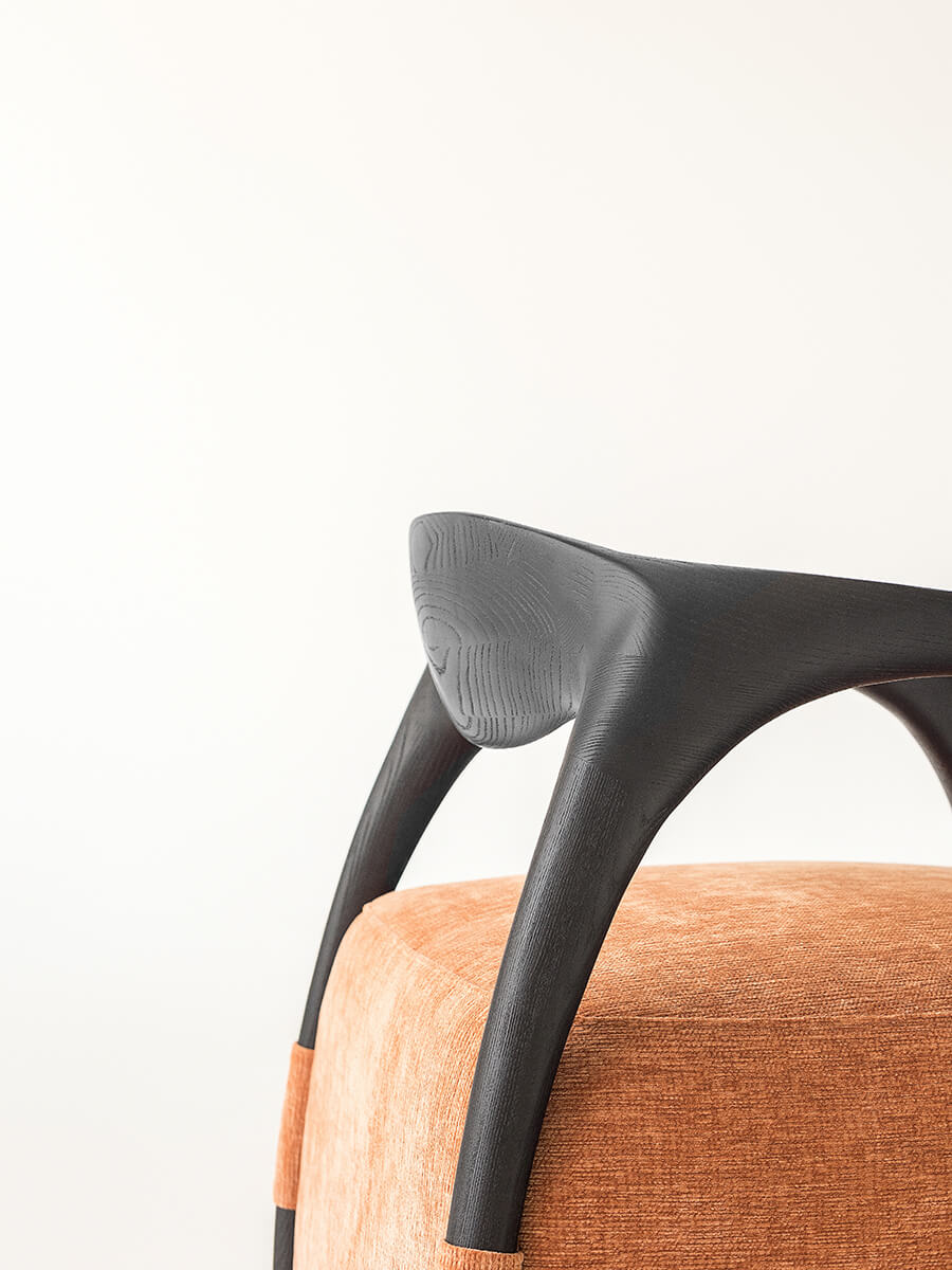 Side angle view of the Eland Armchair with curved timber frame and upholstered seat
