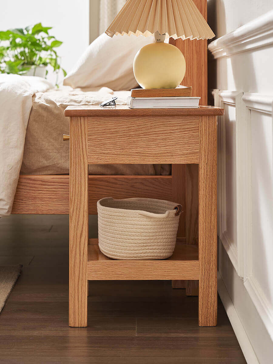 Side view of Gamo solid oak bedside table beside a bed