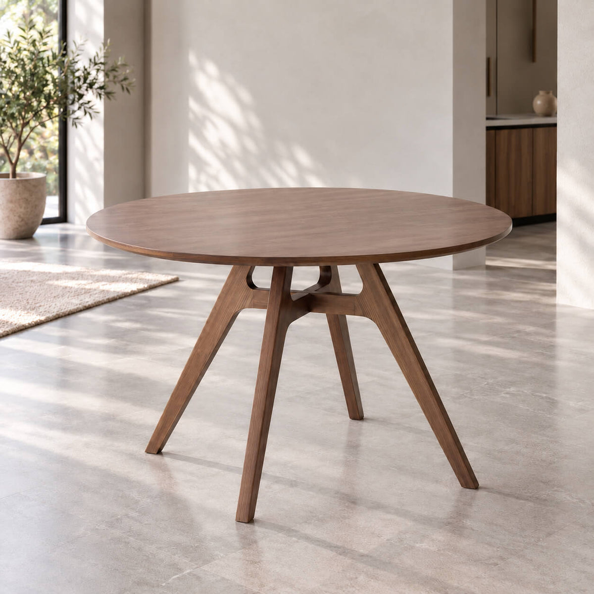 Jacob solid American ash round dining table in walnut stained finish, featuring a sculptural angled-leg base in a minimalist contemporary dining room.