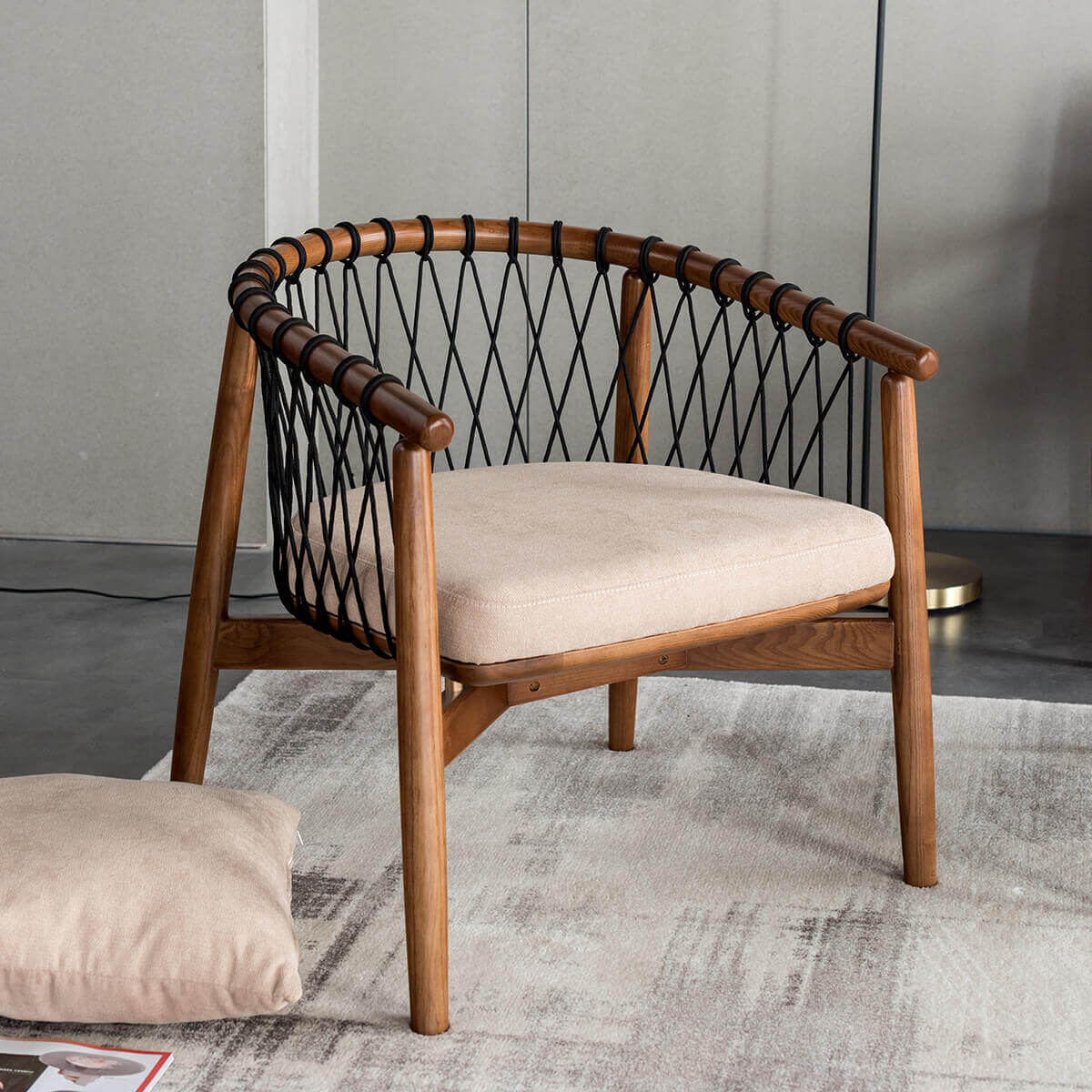 Angled view of the Kniss woven armchair with sculptural timber frame