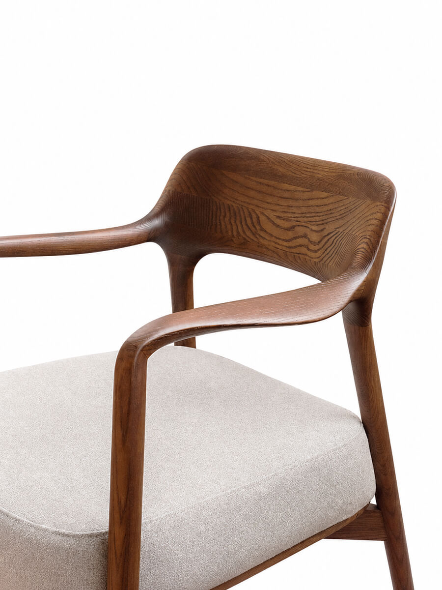 Close-up of the Kyra armchair showing flowing timber arms and seamless craftsmanship