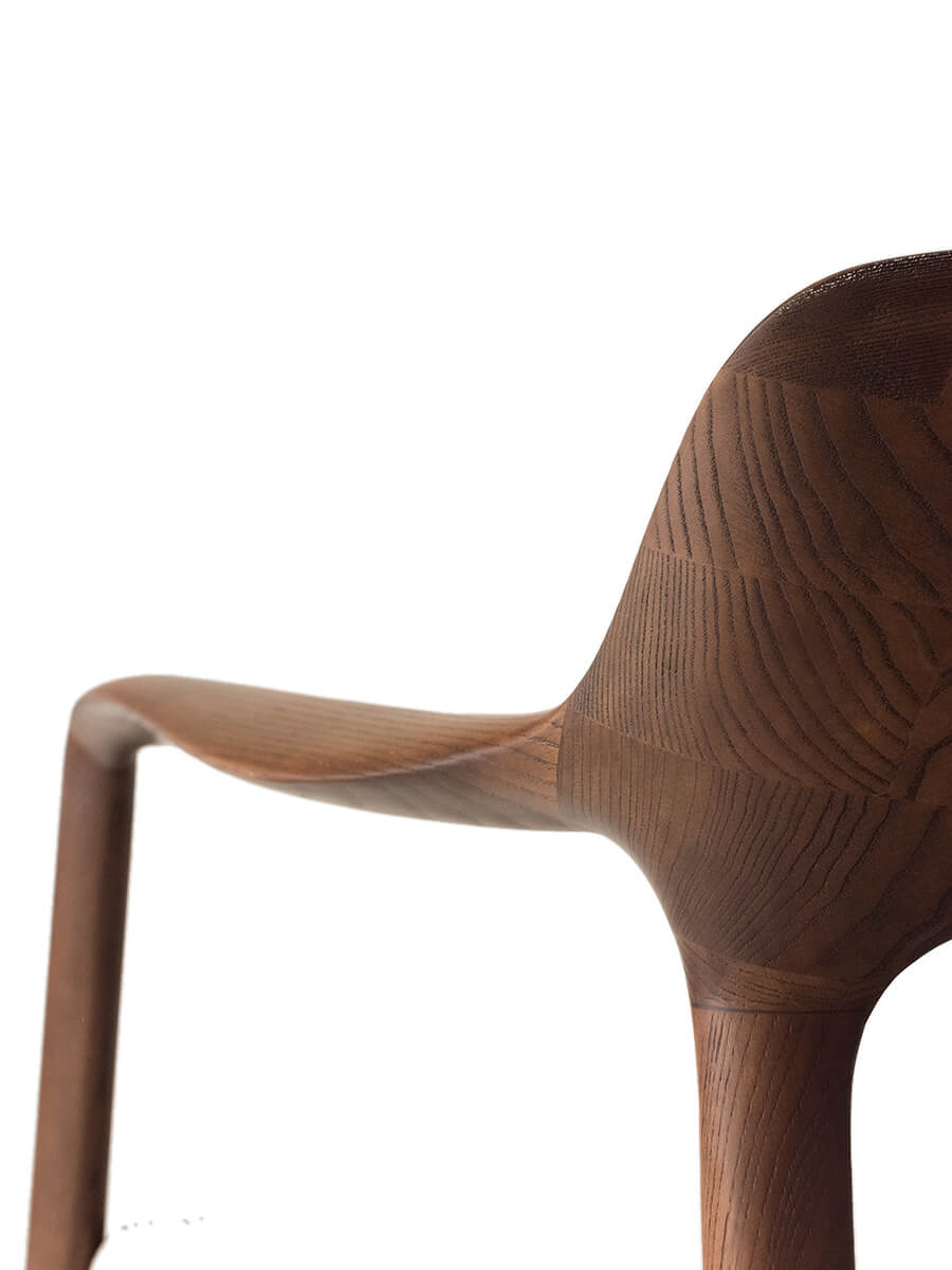 Detail of the Kyra armchair backrest with sculptural solid timber design