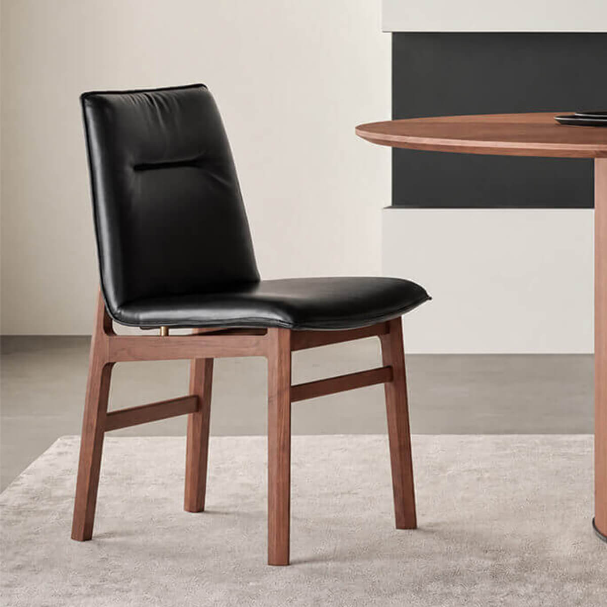 Loren Leather Dining Chair in black leather beside a walnut dining table