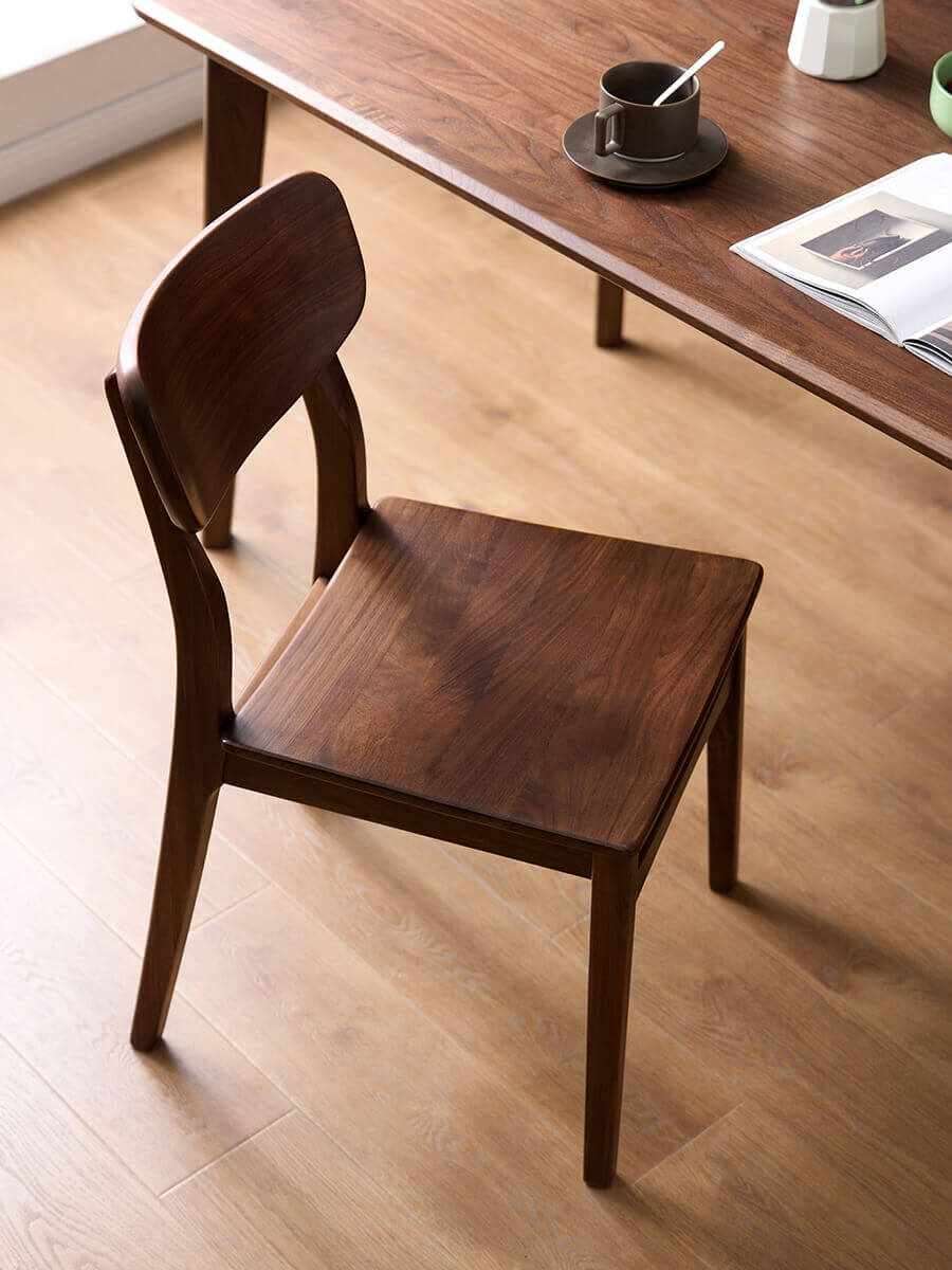Oden Solid Walnut Dining Chair beside a walnut dining table