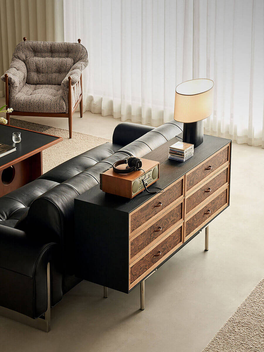 Orven 6 drawer storage chest with burl-effect fronts behind a sofa