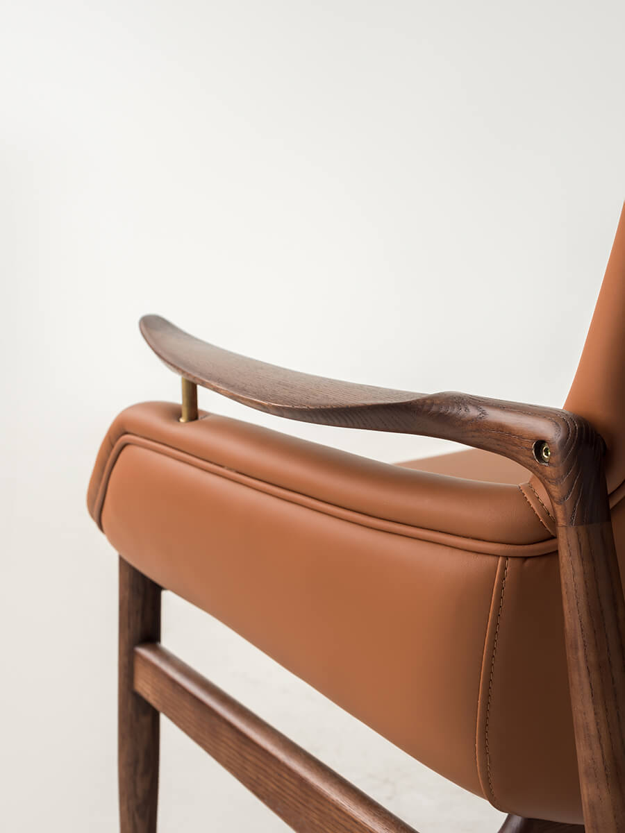 Close-up of sculptural timber armrest on Robin Leather Armchair