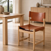 Spanish Dining Chair Replica with saddle leather seat beside natural timber dining table