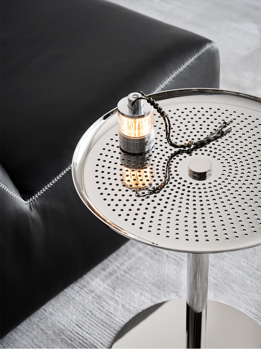 Sterling polished stainless steel side table beside a black leather chair
