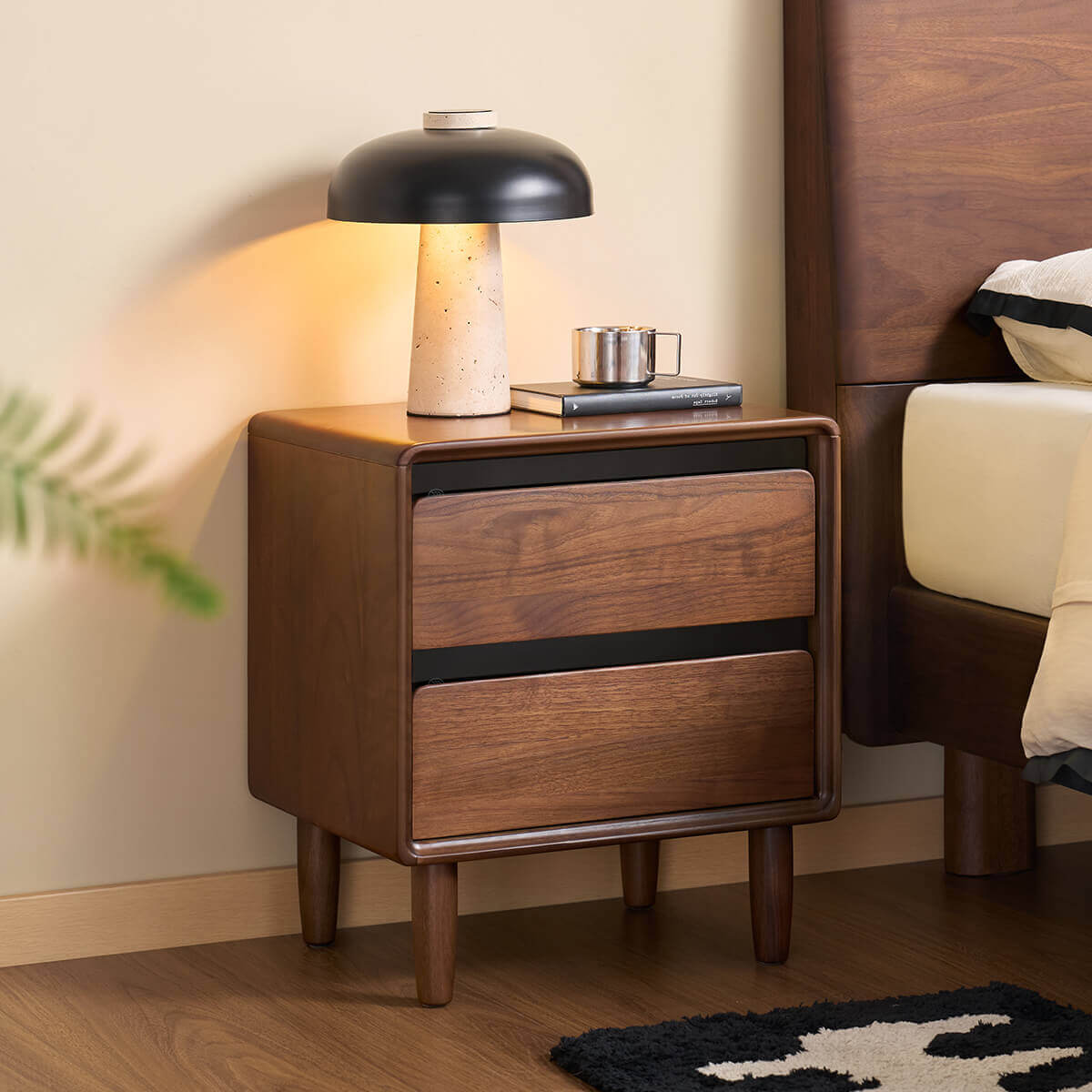 Tura solid walnut bedside table beside a bed with tempered smoked glass detail