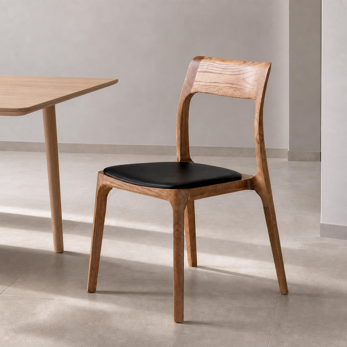 Visby Solid Ash Dining Chair in a modern dining room with natural ash wood grain and black upholstered seat