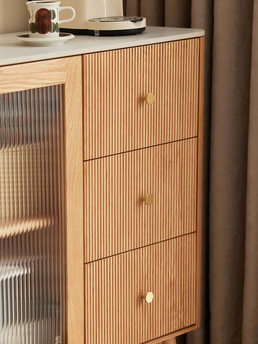 Close-up of Voss solid oak sideboard with three finely grooved drawer fronts and brass handles.