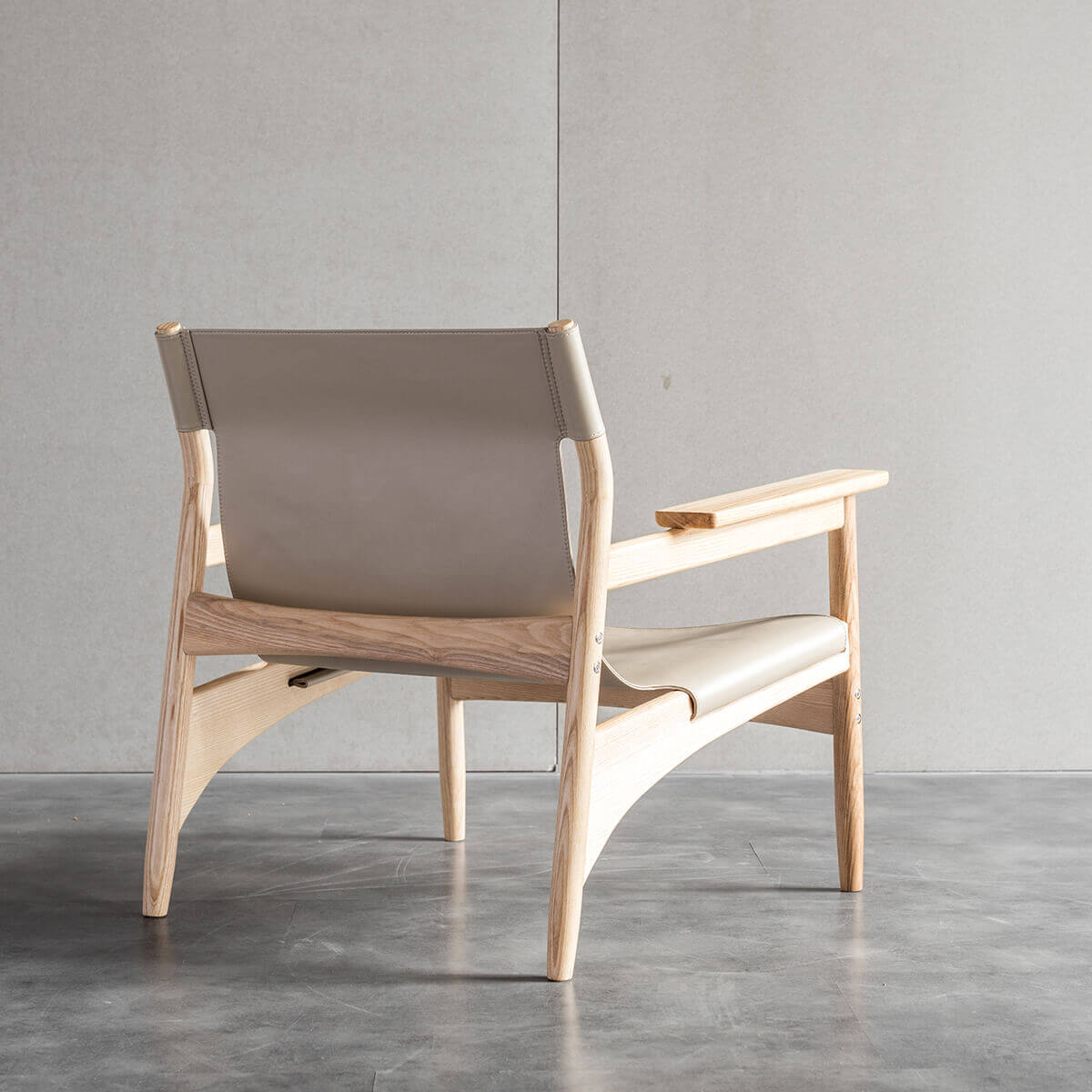 Carey armchair with natural ash timber frame and artificial saddle leather sling seat back view