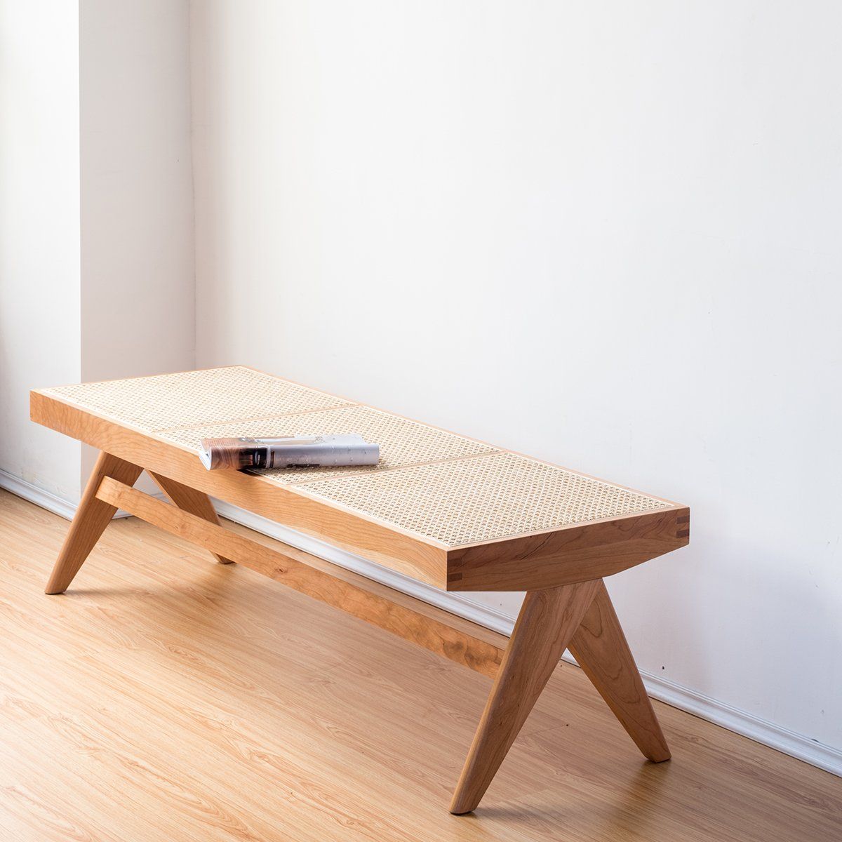 Sandy solid timber bench with natural rattan seat in a minimalist interior