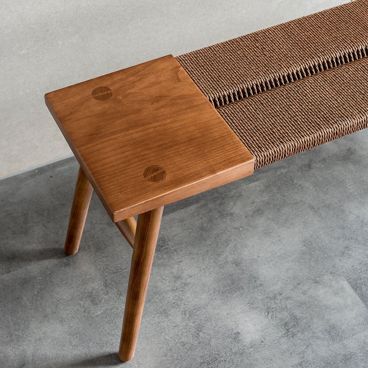 Close-up of the Saro bench in walnut finish with handwoven paper cord seat